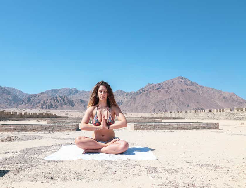 Uma mulher sentada meditando em uma paisagem relaxante.