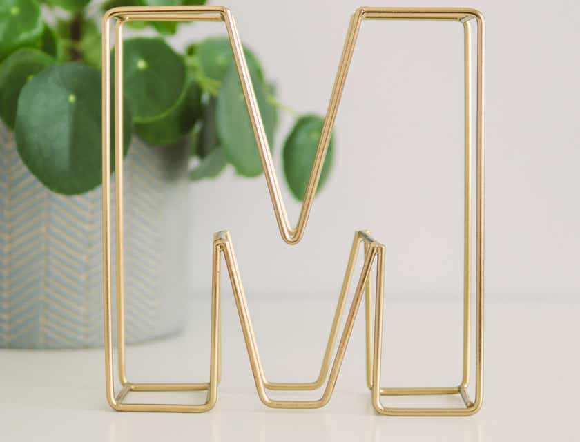 Uma letra "M" em dourado em cima de uma superfície branca.