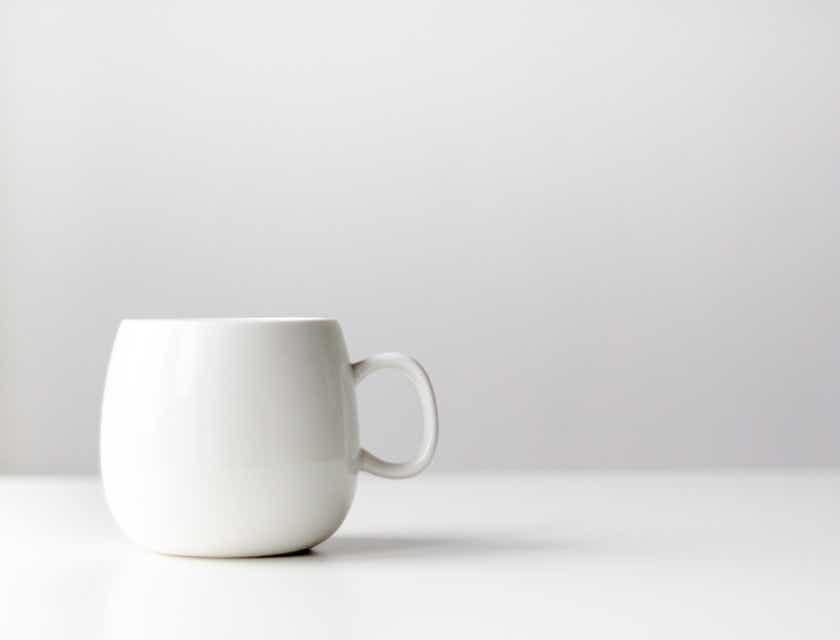 Une tasse minimaliste en céramique blanche sur un fond blanc.