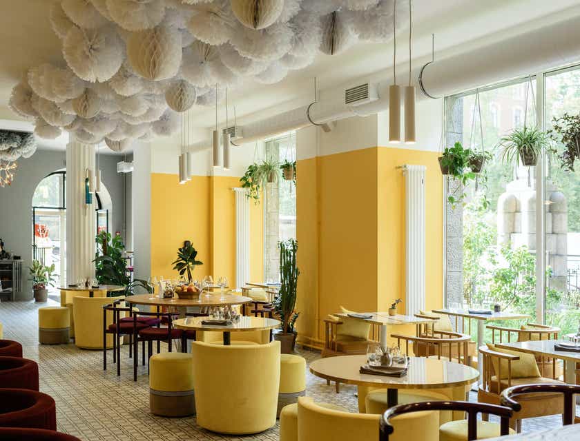 L'interno di un ristorante moderno con mobili e decorazioni in giallo e grandi finestre.