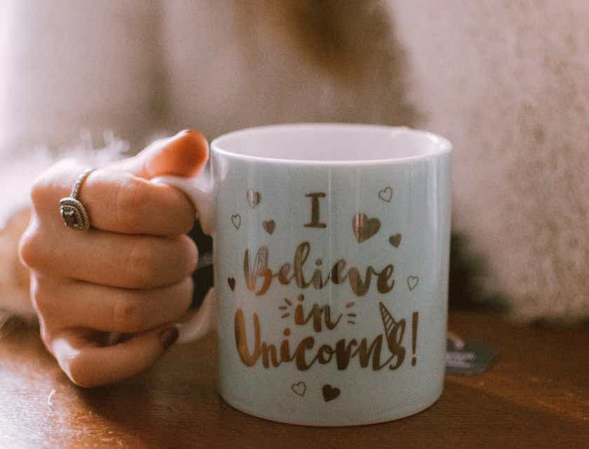 Una mujer sosteniendo una taza que dice "Creo en los unicornios" en un logo de taza.