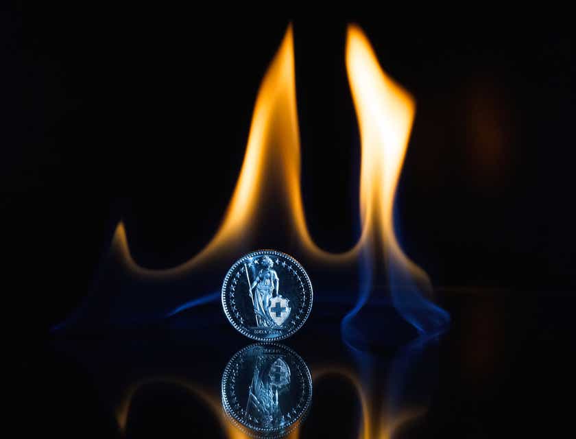 Een munt omgeven door een vlam, tegen een donkere achtergrond.