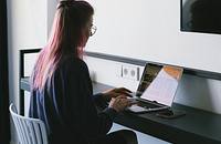 A news journalist working on their laptop at a desk.