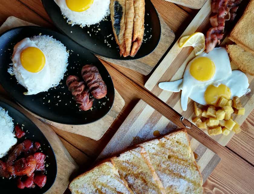 Een rij borden met ontbijt op een ontbijttafel.