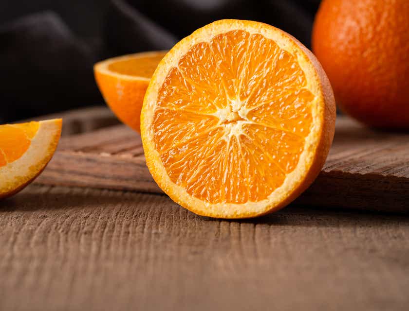 Une orange coupée en tranches sur une surface en bois.