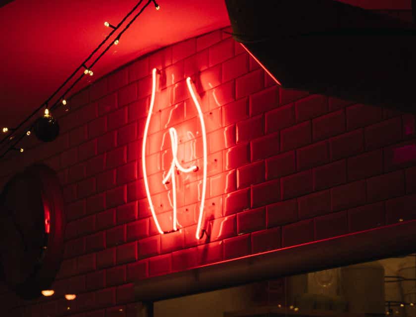 Prowokacyjny neon przedstawiający kształt pośladków w ciemnym pomieszczeniu.