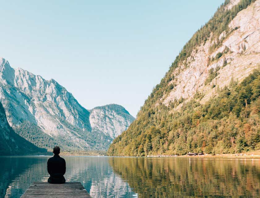 Una persona seduta sul pontile di un lago, immerso in un'atmosfera quieta.