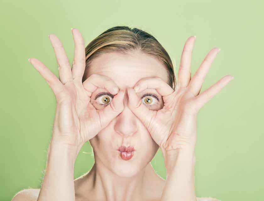 Eine Frau zieht ein Gesicht und formt mit ihren Fingern eine Brille, um einen skurrilen Eindruck zu hinterlassen.