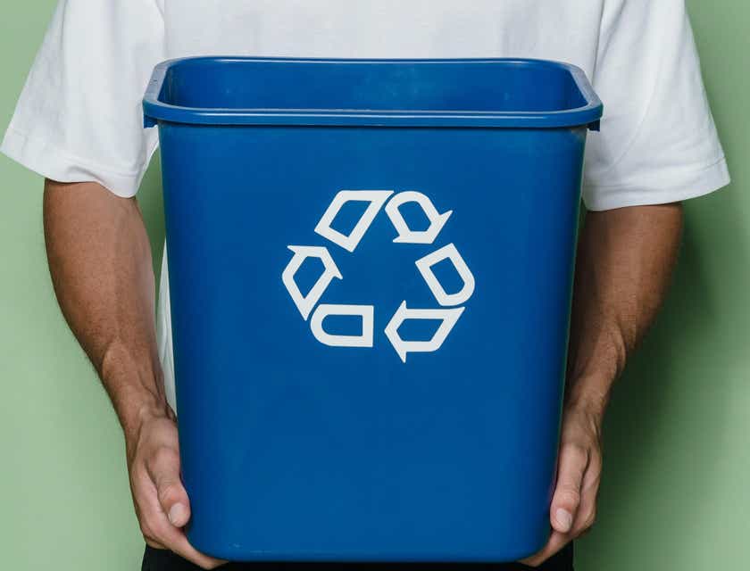A man holding up a blue recycling bin.