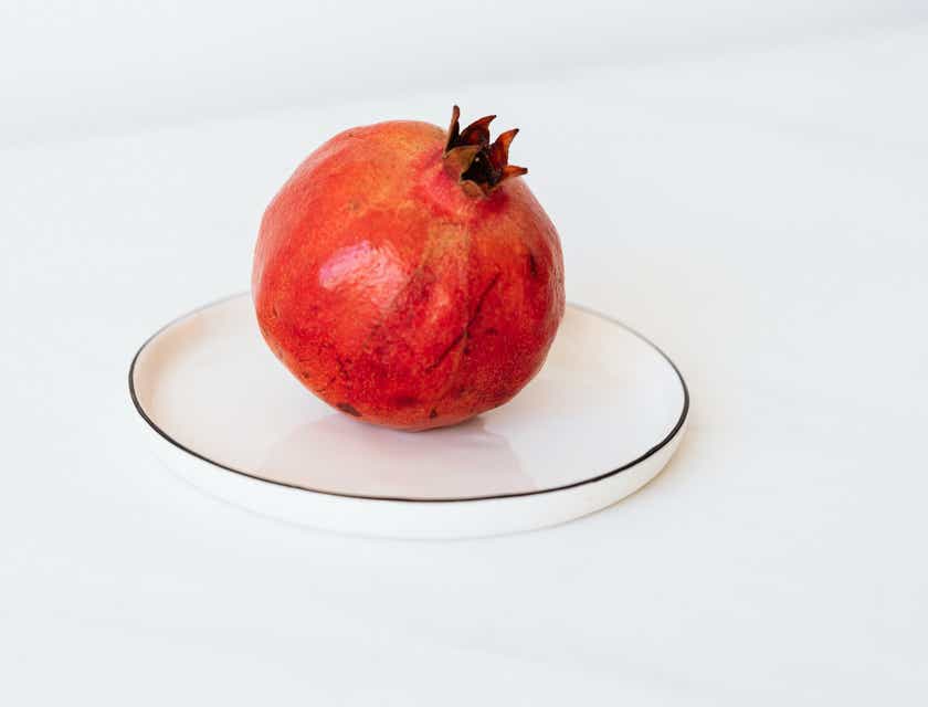 Owoc granatu na białym talerzu, przypominający czerwone koło.