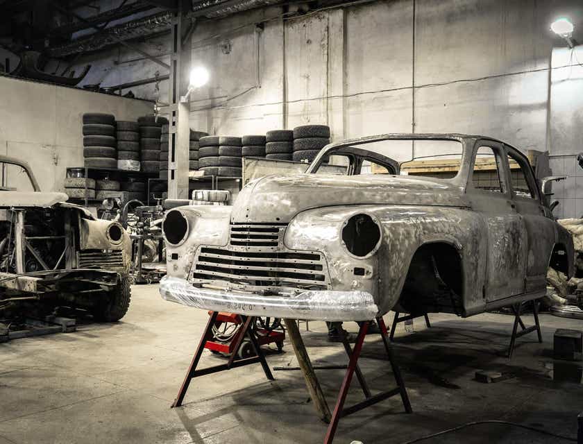 La carrosserie d'une vieille voiture sur des vérins dans une entreprise de restauration de voitures.