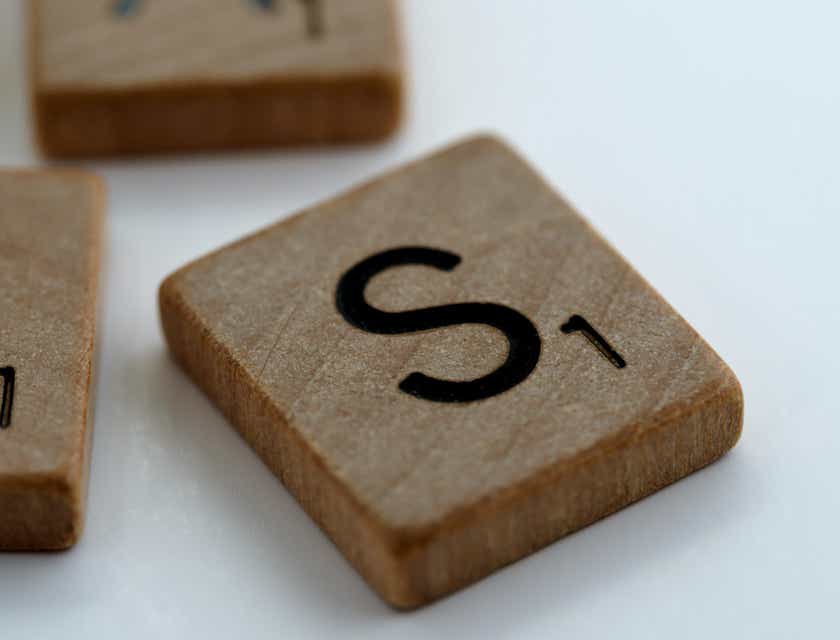 A wooden scrabble piece with the letter "S."
