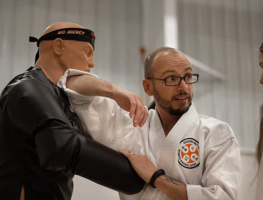 A self-defense instructor demonstrating a technique on a dummy.
