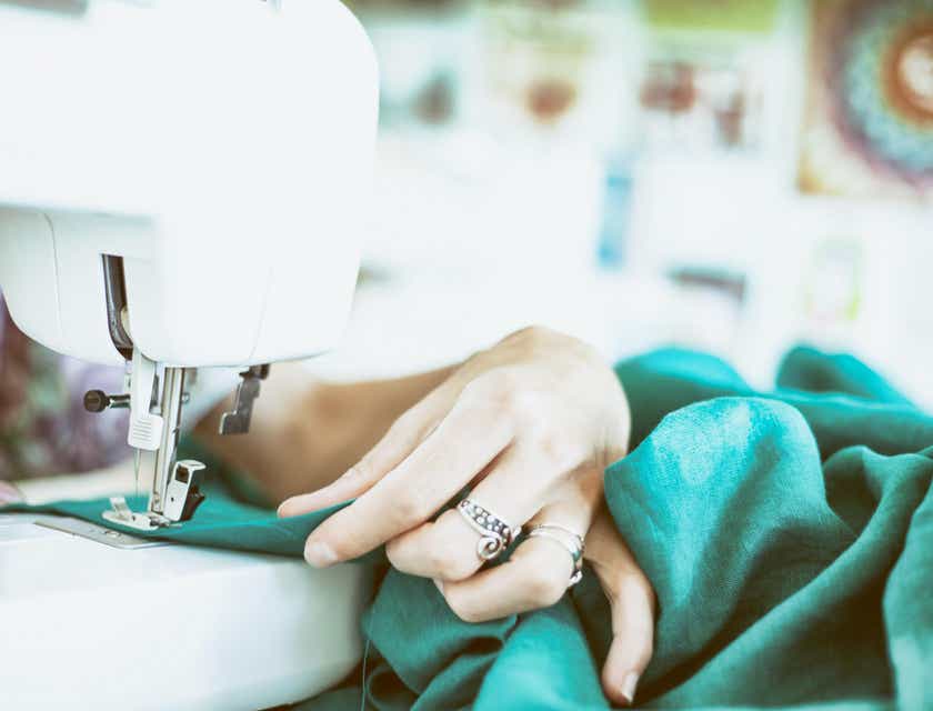Una persona cosiendo una prenda azul en un logo para costura.