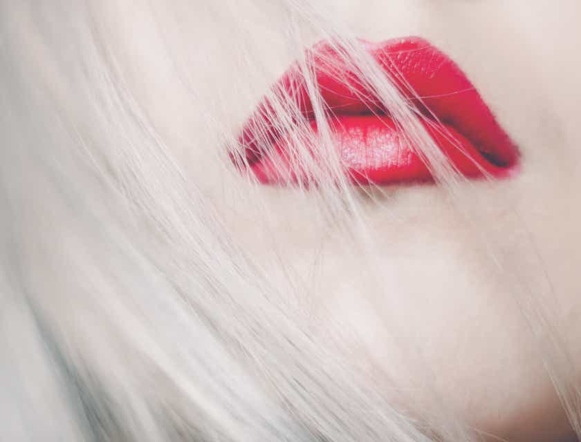 Les cheveux blonds d'une personne flottant devant ses lèvres rouges.