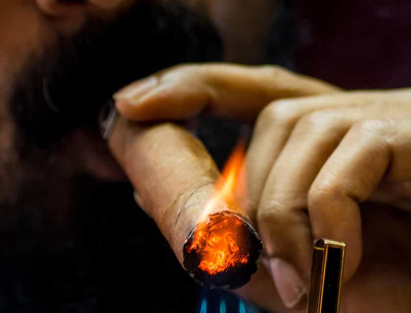 Ein Mann zündet mit einem goldenen Feuerzeug in einem Tabakladen eine Zigarre an.
