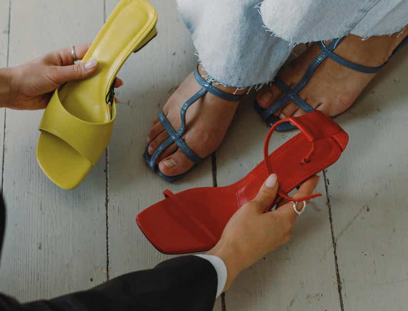 Uno stilista che fa vedere diverse scarpe a un cliente.