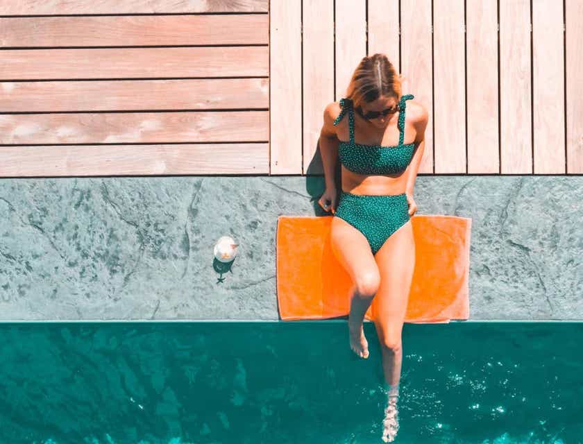 Une femme en train de bronzer au bord de la piscine.