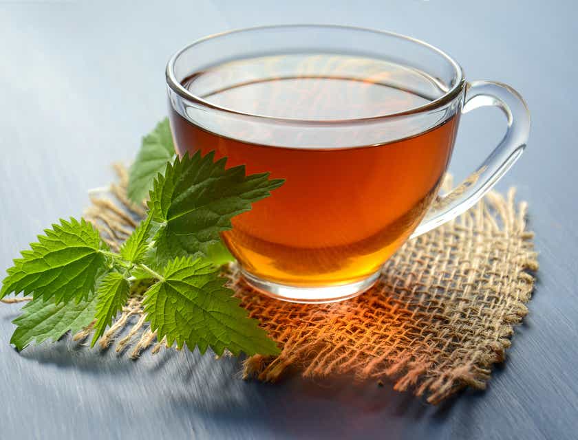 Una taza de té caliente con una decoración de hojas a un lado en un logo de té.