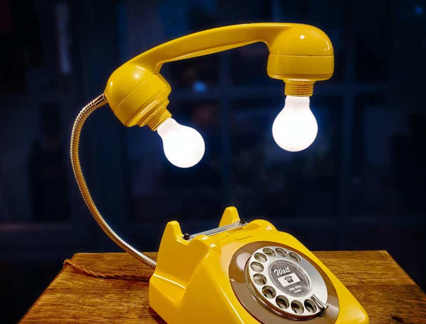 Un teléfono rotatorio amarillo reciclado con bombillas que sobresalen conectadas al receptor en un logo para suprareciclaje.