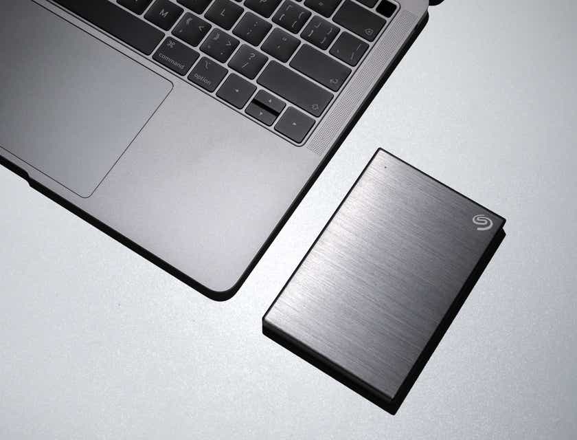 A laptop on a white table and an external hard disk used for data recovery.