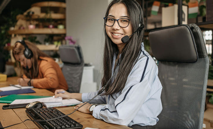 Virtual assistant with headphones working at their desk.