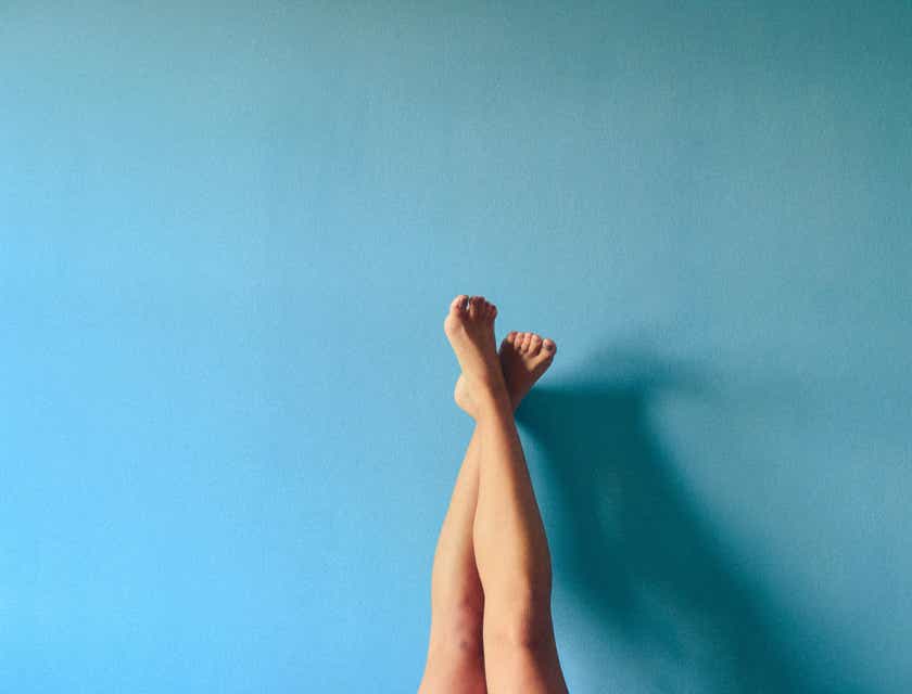 Un par de piernas de piel sedosa apoyadas contra una pared azul en un logo de depilación.