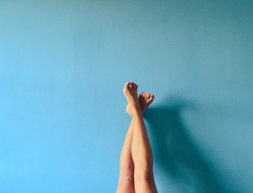 Mavi bir duvara yaslanmış yeni ağda yapılmış bacaklar.