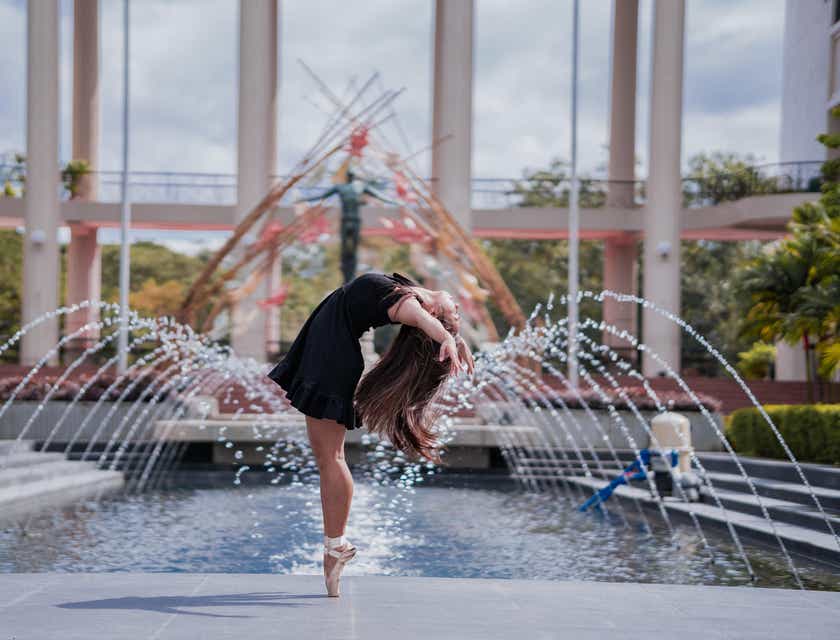 Una donna sulle punte che balla di fronte a una fontana particolare.
